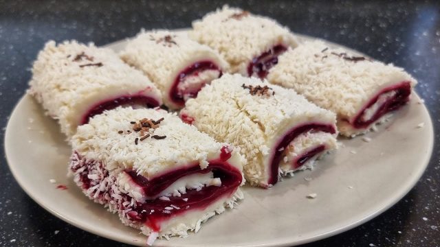 Rulouri delicioase de cocos fără coacere. Crema pufoasă de vanilie se combină cu un strat ușor acrișor de cireșe, totul învelit în nucă de cocos rasă fin